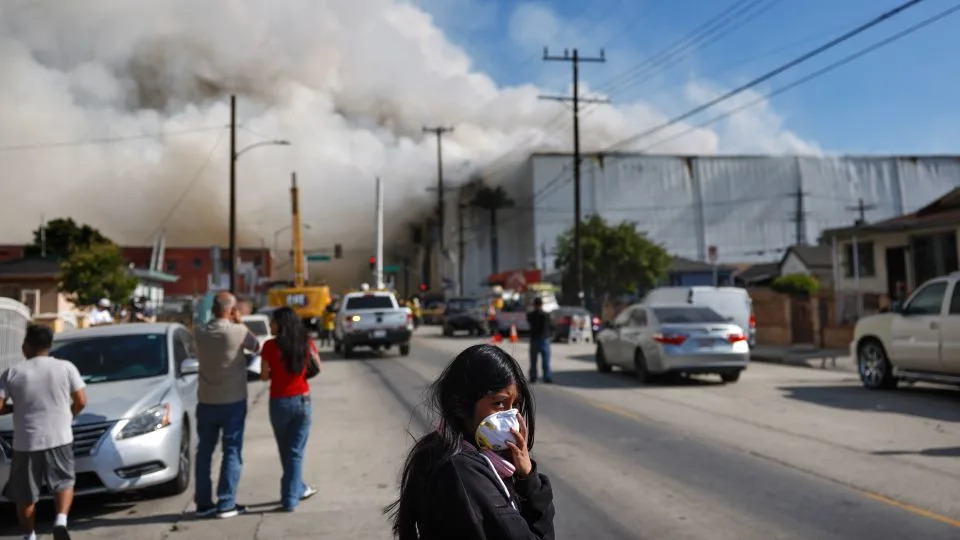 An onlooker wears a face mask near the smoldering warehouse Saturday, three days after a fire began. - Mario Tama/Getty Images