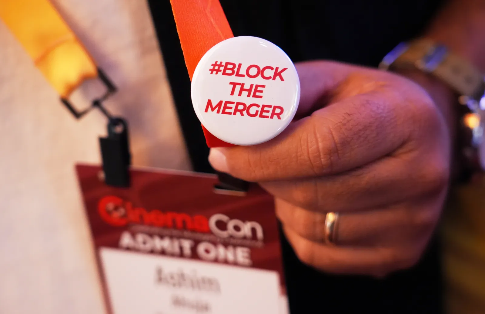 A CinemaCon attendee sports a pin expressing opposition to the proposed Paramount-Warner Bros. Discovery merger during CinemaCon 2026 on April 14 at Caesars Palace in Las Vegas. (AP Photo/Chris Pizzello)