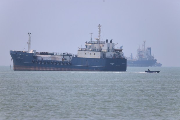 A small motorboat passes anchored vessels in the Strait of Hormuz.