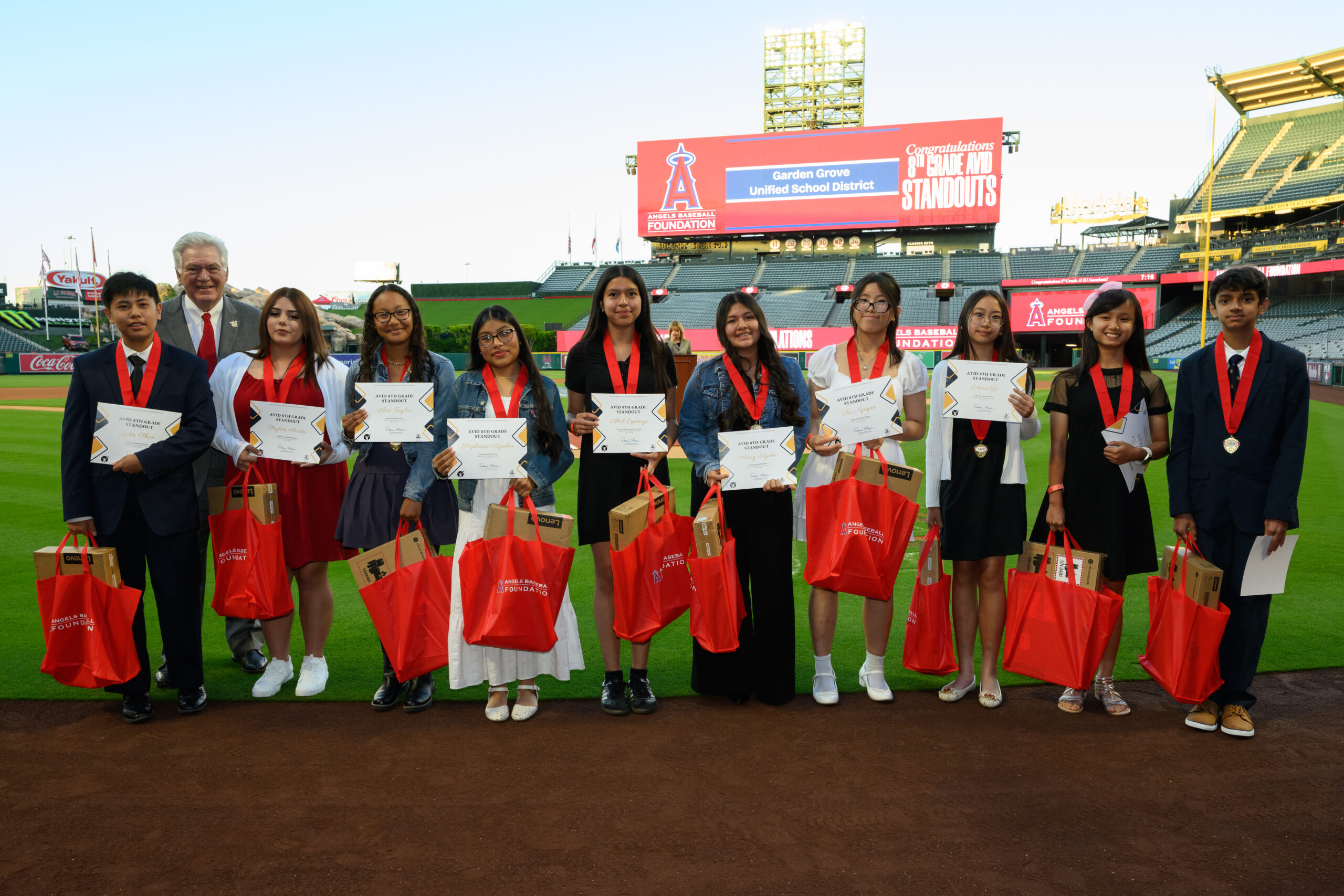 Dennis Kuhl, chairman of Angels Baseball, poses with students recognized during the 2026 AVID 8th Grade Standout Recognition ceremony at Angel Stadium.
