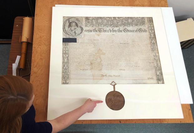 Archivist Ashley Selima points to the seal of King George III. 