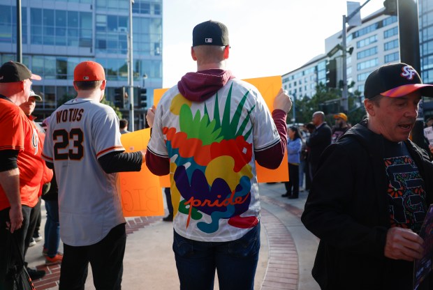 Protesters, including Noah Wallace, center, from San Francisco, hold up signs in reaction to San Francisco Giants' players recently writing on Pride-themed hats, outside of Oracle Park before the San Francisco Giants and the Athletics game in San Francisco, Calif., on Tuesday, June 23, 2026. (Nhat V. Meyer/Bay Area News Group)