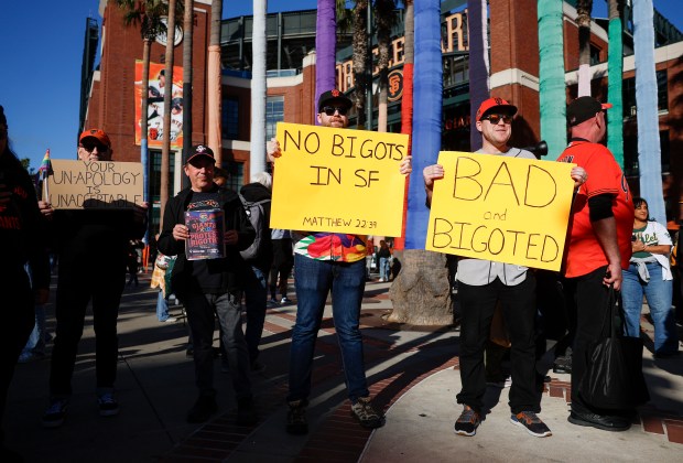 Protesters, including Noah Wallace, center, from San Francisco, hold up signs in reaction to San Francisco Giants' players recently writing on Pride-themed hats, outside of Oracle Park before the San Francisco Giants and the Athletics game in San Francisco, Calif., on Tuesday, June 23, 2026. (Nhat V. Meyer/Bay Area News Group)
