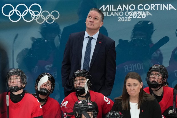 Canada head coach Troy Ryan, top center, watches a replay during the second period of a women's ice hockey semifinal match against Switzerland at the 2026 Winter Olympics, in Milan, Italy, Monday, Feb. 16, 2026. (AP Photo/Carolyn Kaster)