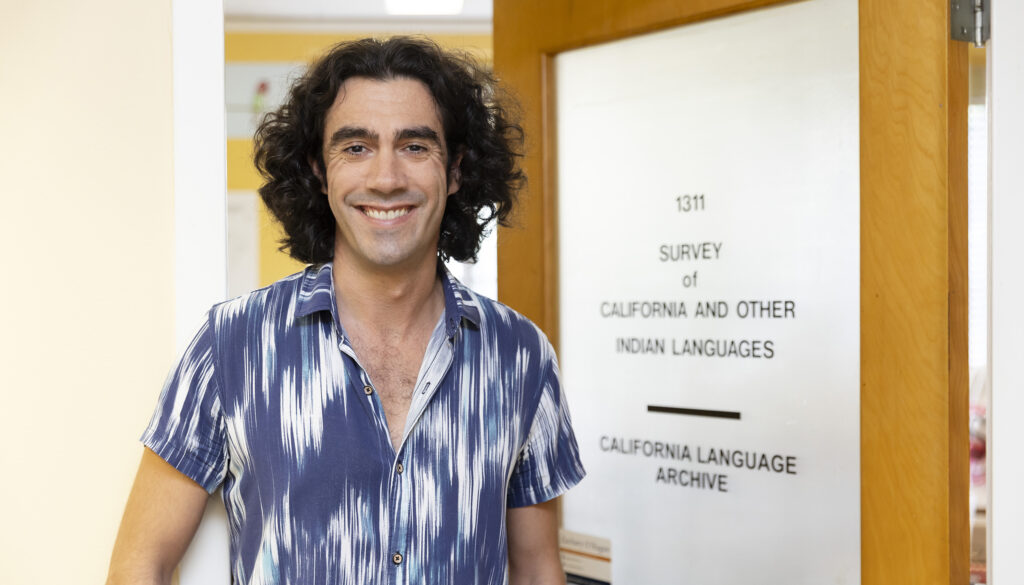 A portrait of Zachary O'Hagan standing next to the door that leads into the California Language Archive.