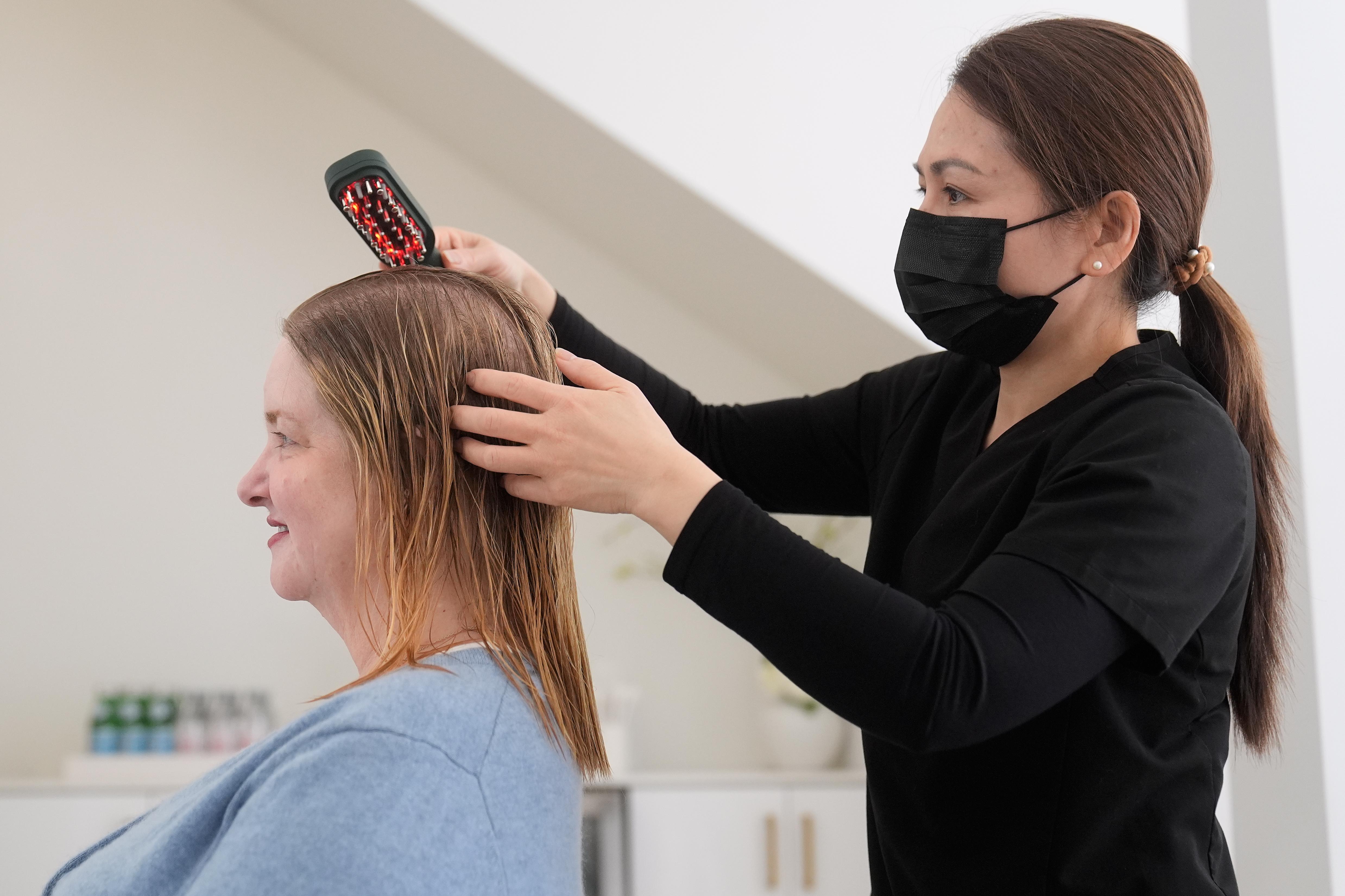 Head spa specialist Ha Truong, right, uses a Red and...
