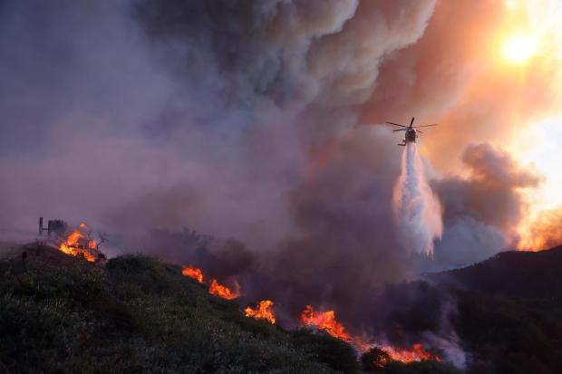 Water is dropped by helicopter on the advancing Palisades Fire.