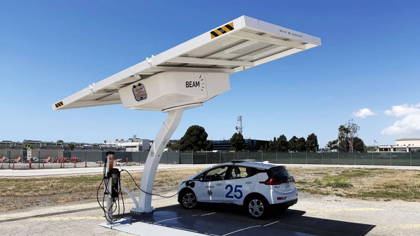 A white electric vehicle charging at a solar-powered station.