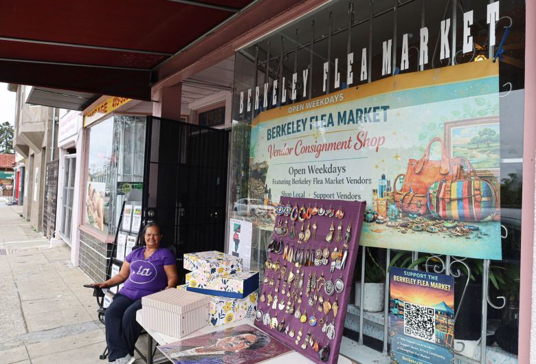 A woman sits in a chair outside a shop with a sign that reads, "Berkeley Flea Market"