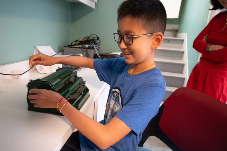boy sitting at desk using brailler