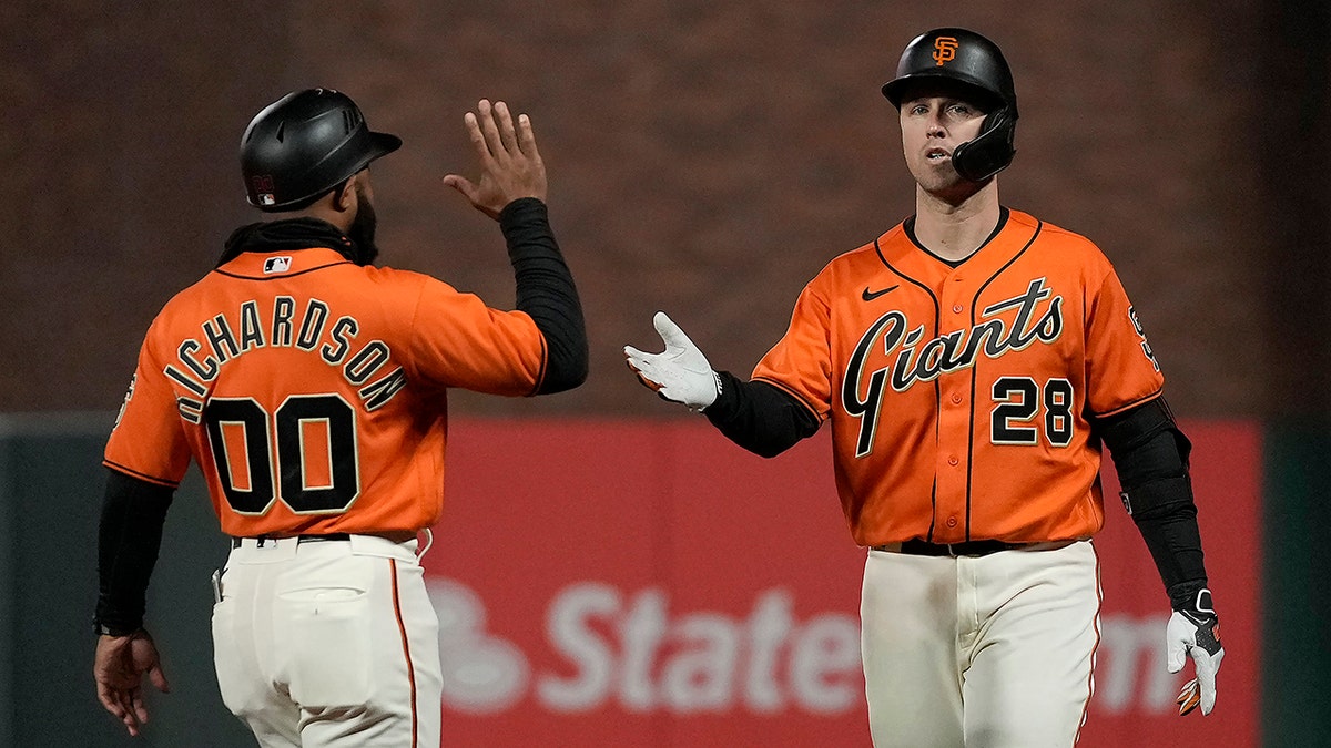 San Francisco Giants' Buster Posey beats throw to first base with coach Antoan Richardson congratulating him