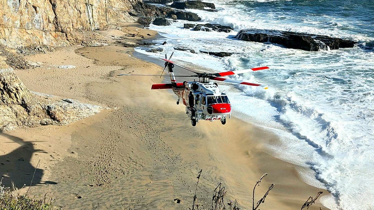 helicopter flying over coastline at a beach