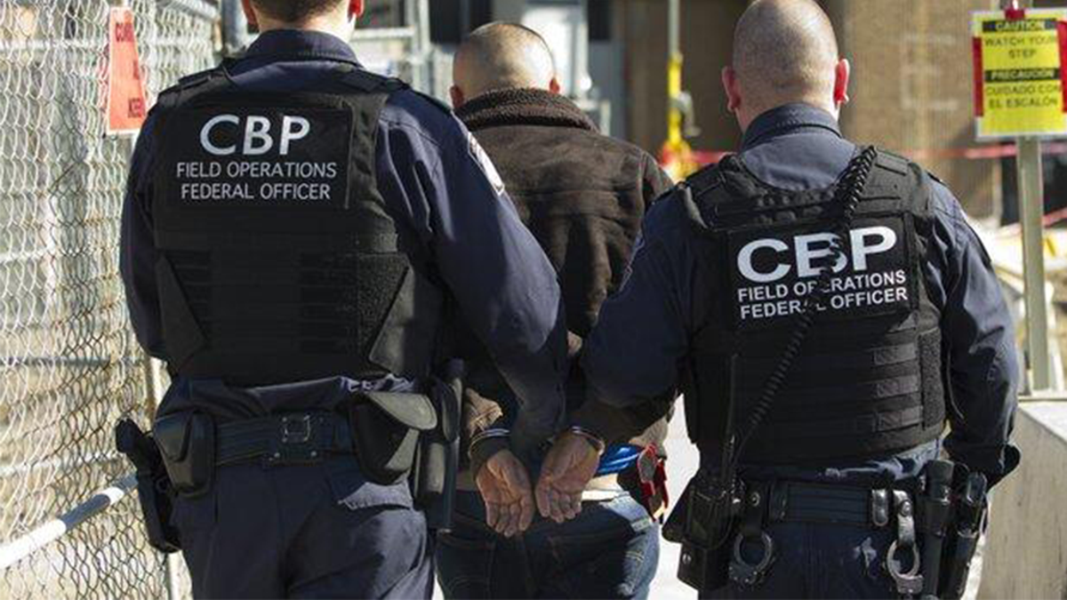 CBP officers escort a wanted person at a U.S. port of entry