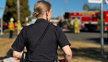 An officer in uniform and a red fire engine in the background