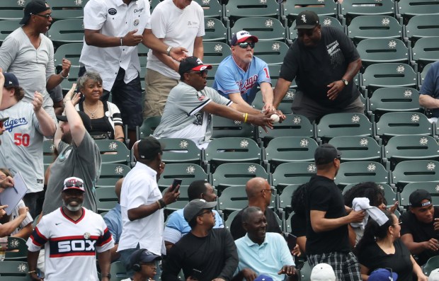 Fans reach for a home run ball hit by Dodgers designated hitter Shohei Ohtani in the first inning against the White Sox on June 13, 2026, at Rate Field. (John J. Kim/Chicago Tribune)