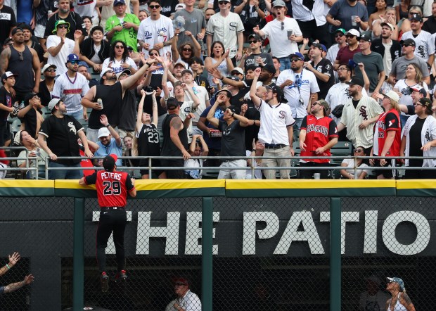 White Sox center fielder Tristan Peters leaps onto the fence as fans reach for a two-run home run ball hit by Dodgers third baseman Max Muncy in the eighth inning on June 13, 2026, at Rate Field. (John J. Kim/Chicago Tribune)
