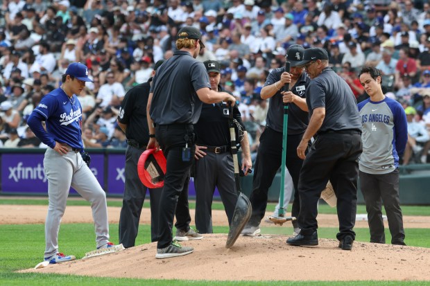 Dodgers starter Yoshinobu Yamamoto, left, watches as grounds-crew workers level the mound in the sixth inning against the White Sox on June 13, 2026, at Rate Field. (John J. Kim/Chicago Tribune)