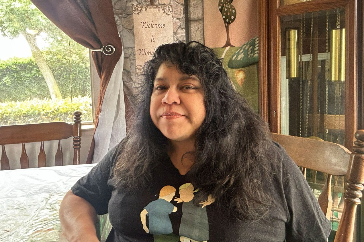 A woman sits at a dining room table.