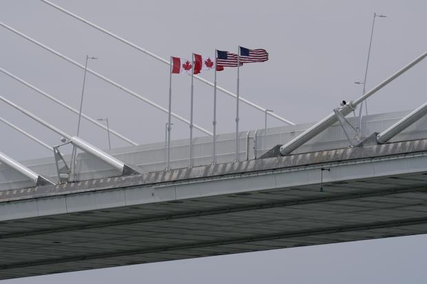 Canadian and American flags are shown on the Gordie Howe Bridge under construction.