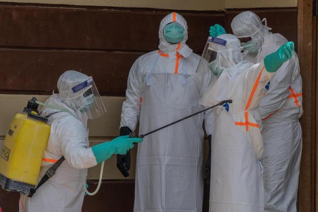 Health workers disinfect themselves after preparing the body of an Ebola victim.