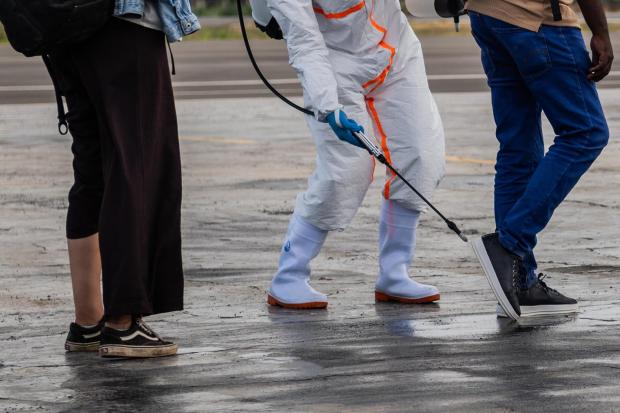 A health worker disinfects passengers prior to their boarding of the World Food Programme's (WFP) aircraft following the government's announcement of Bunia National Airport's reopening in Bunia, Congo, Tuesday, June 2, 2026. (AP Photo/Moses Sawasawa)