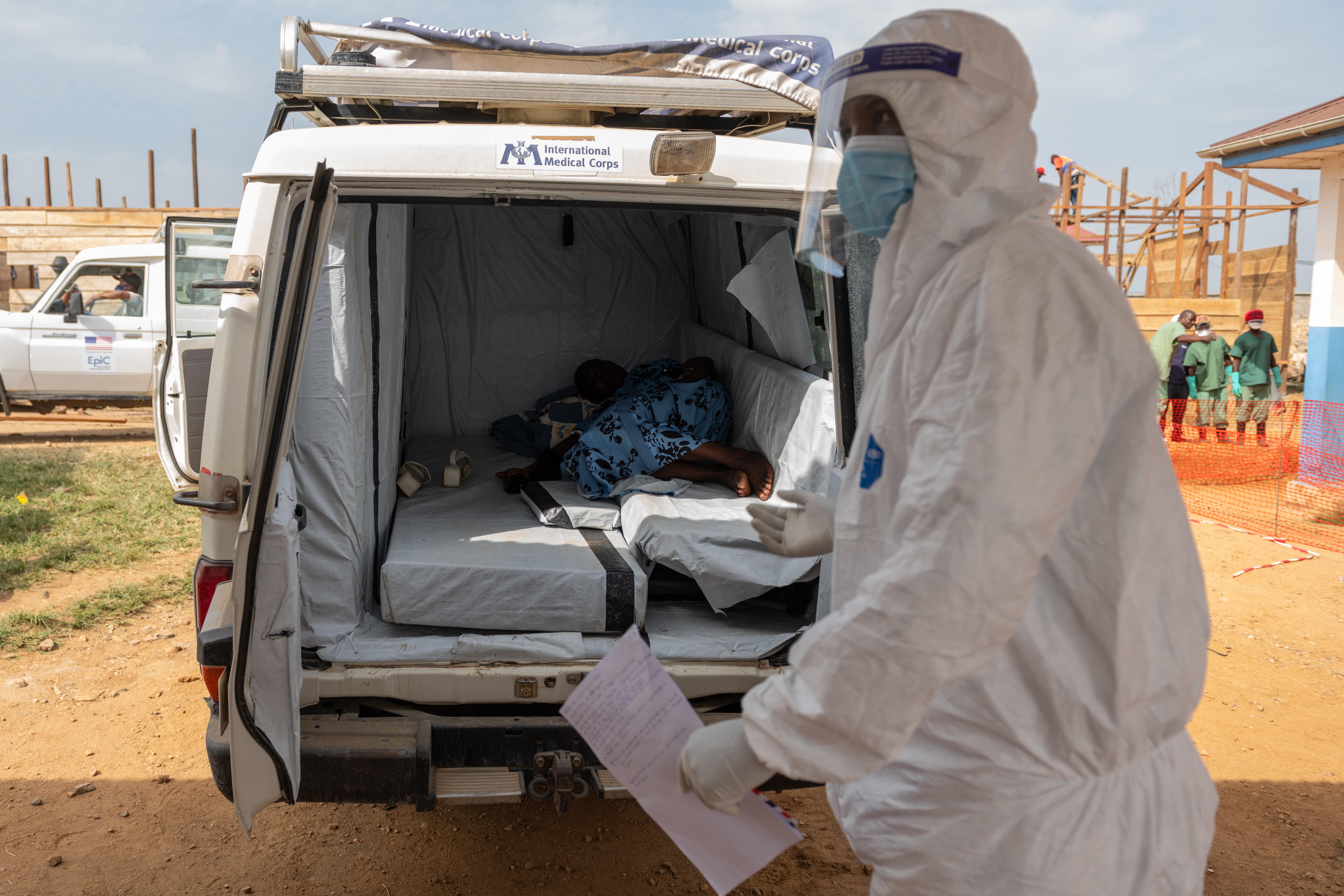 A paramedic stands by a suspected Ebola patient lying in...