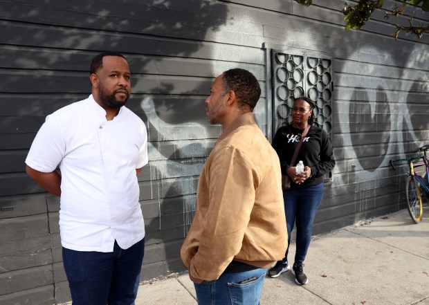 Owner and chef Matt Horn, left, talks with City Administrator Jestin Johnson in front of graffiti at Horn Barbecue in Oakland after a devastating fire that gutted the restaurant in late November 2023. (Jane Tyska/Bay Area News Group)