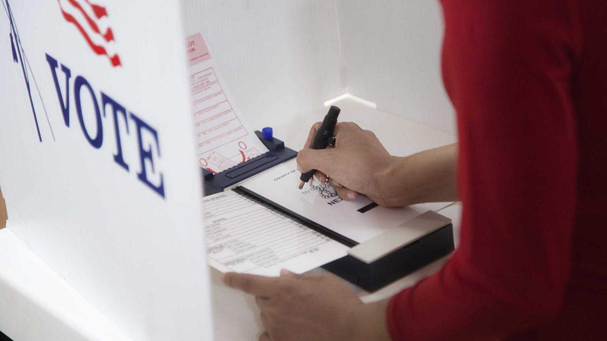 A voter pushes a pin to indicate a vote on a ballot in a voting center during an election.