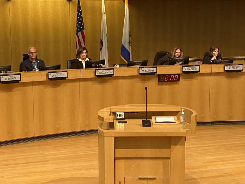 A podium stands in front of a dais with five seats and four people.