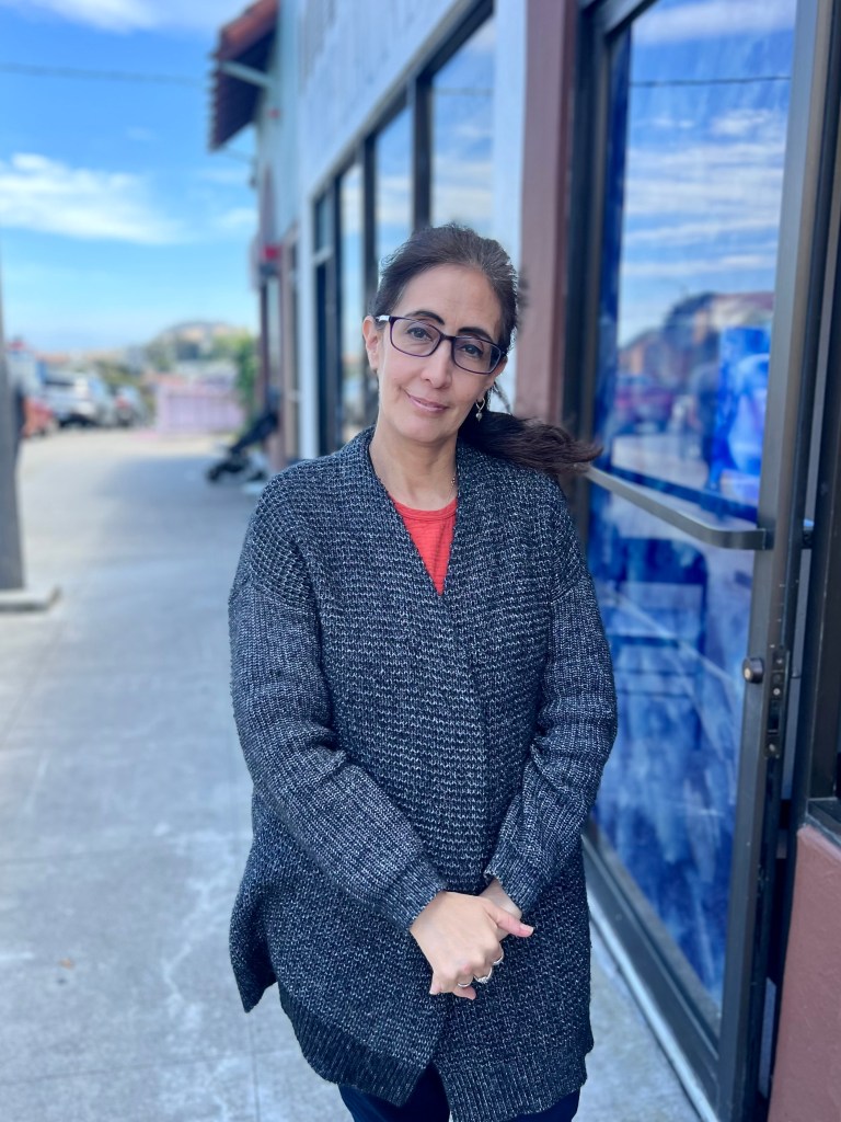 Woman standing in front of clinic doorway smiling softly