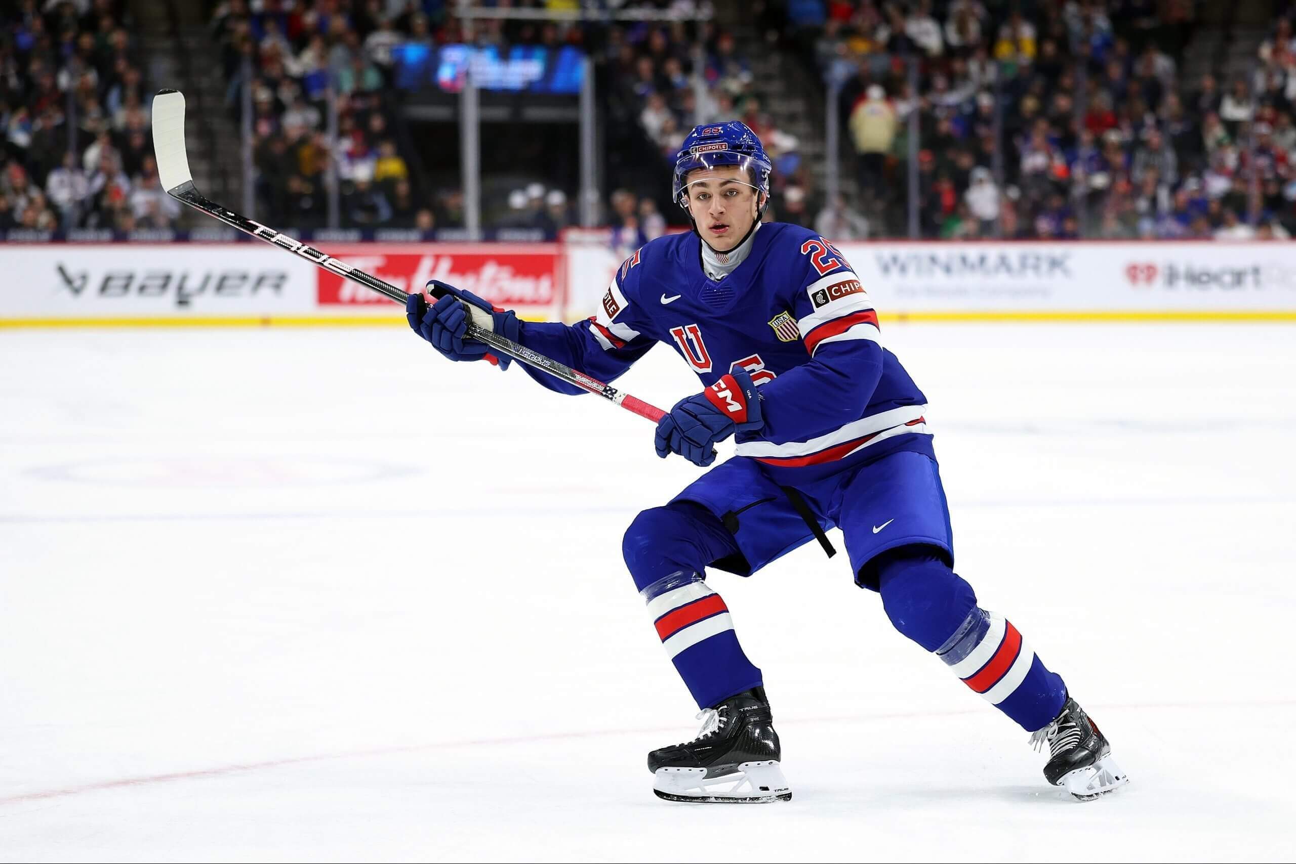 Chase Reid of the United States skates against Sweden with his stick raised in the IIHF World Junior Hockey Championship in December.