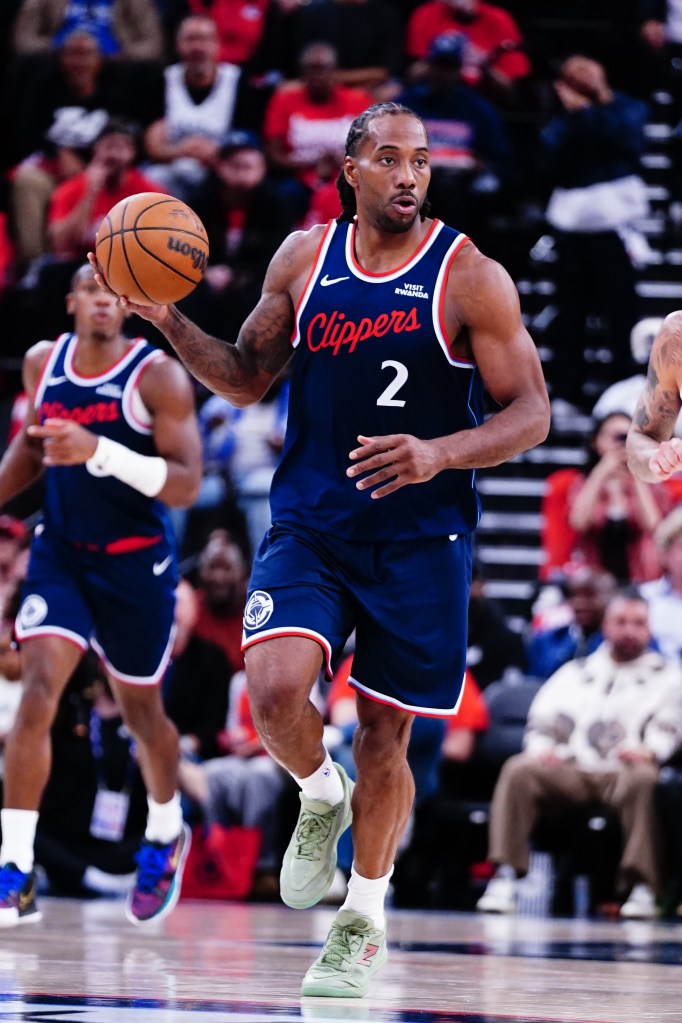 Basketball player Kawhi Leonard dribbles the ball on the court while wearing a blue Clippers jersey with the number 2.