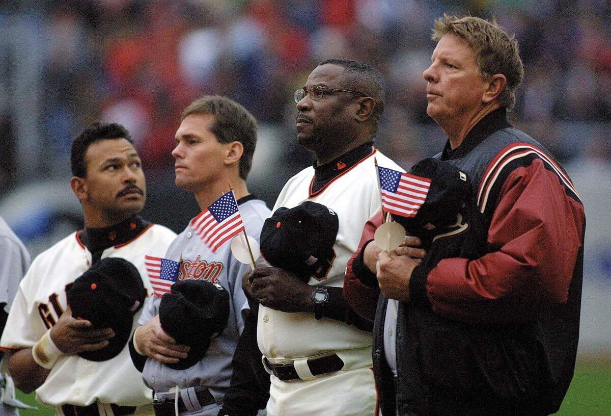 The San Francisco Giants' Marvin Benard, left, looks into the stands as he stands with the Houston Astros' Craig Biggio, Giants manager Dusty Baker and Astros manager Larry Dierker, right, before a game on Sept. 18, 2001.