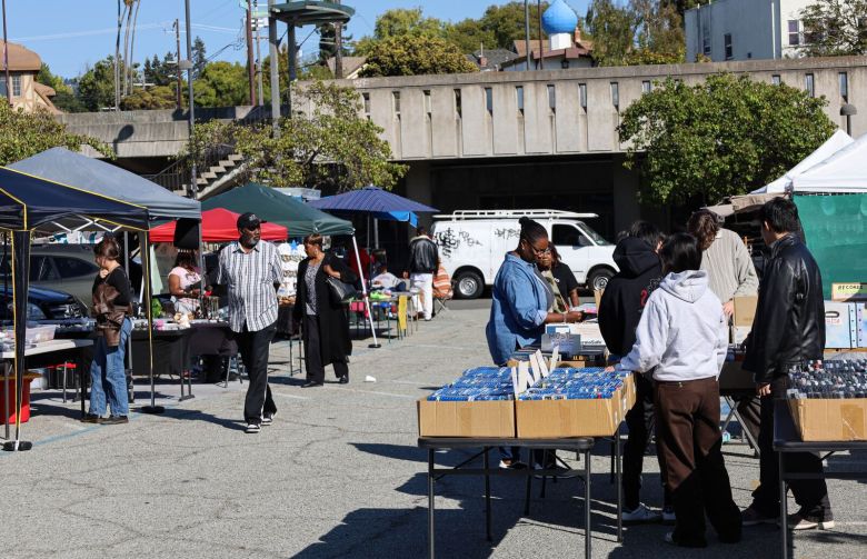 Vendors sell goods at a flea market in a large parking lot