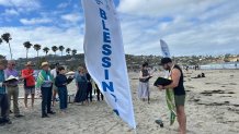 Rev. Tim Seery (right) began Sunday's beach service with a traditional prayer before blessing surfers and their boards, La Jolla, Calif., June 28, 2026.