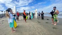 Church members hold their surfboards during a Sunday morning service at La Jolla Shores, June 28, 2026.