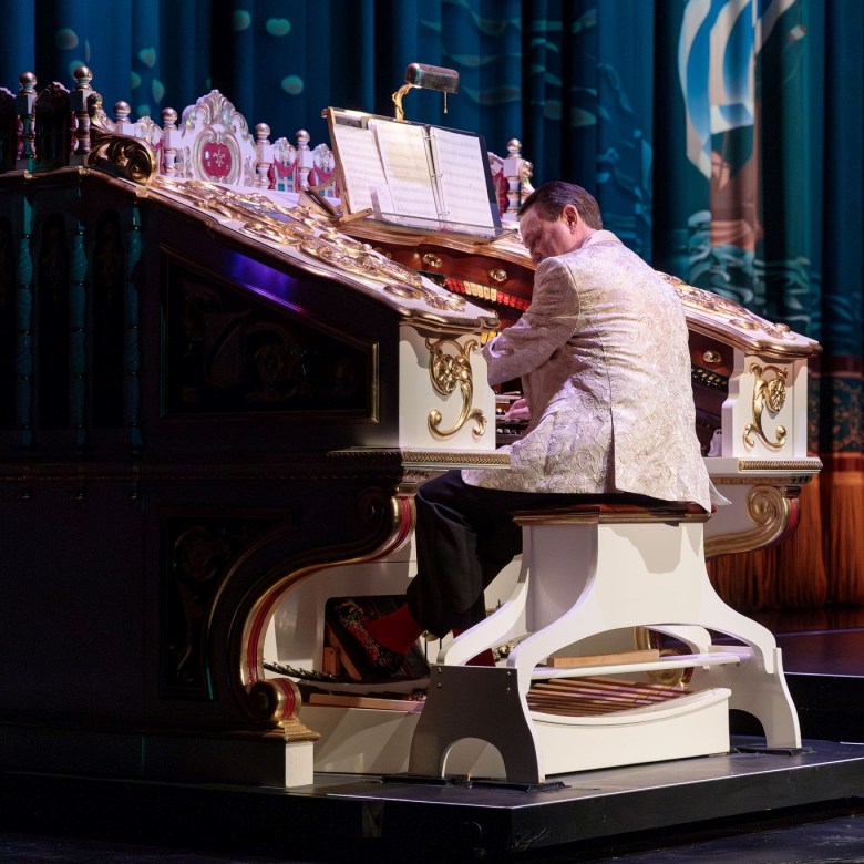 Man in white suit plays fancy white organ
