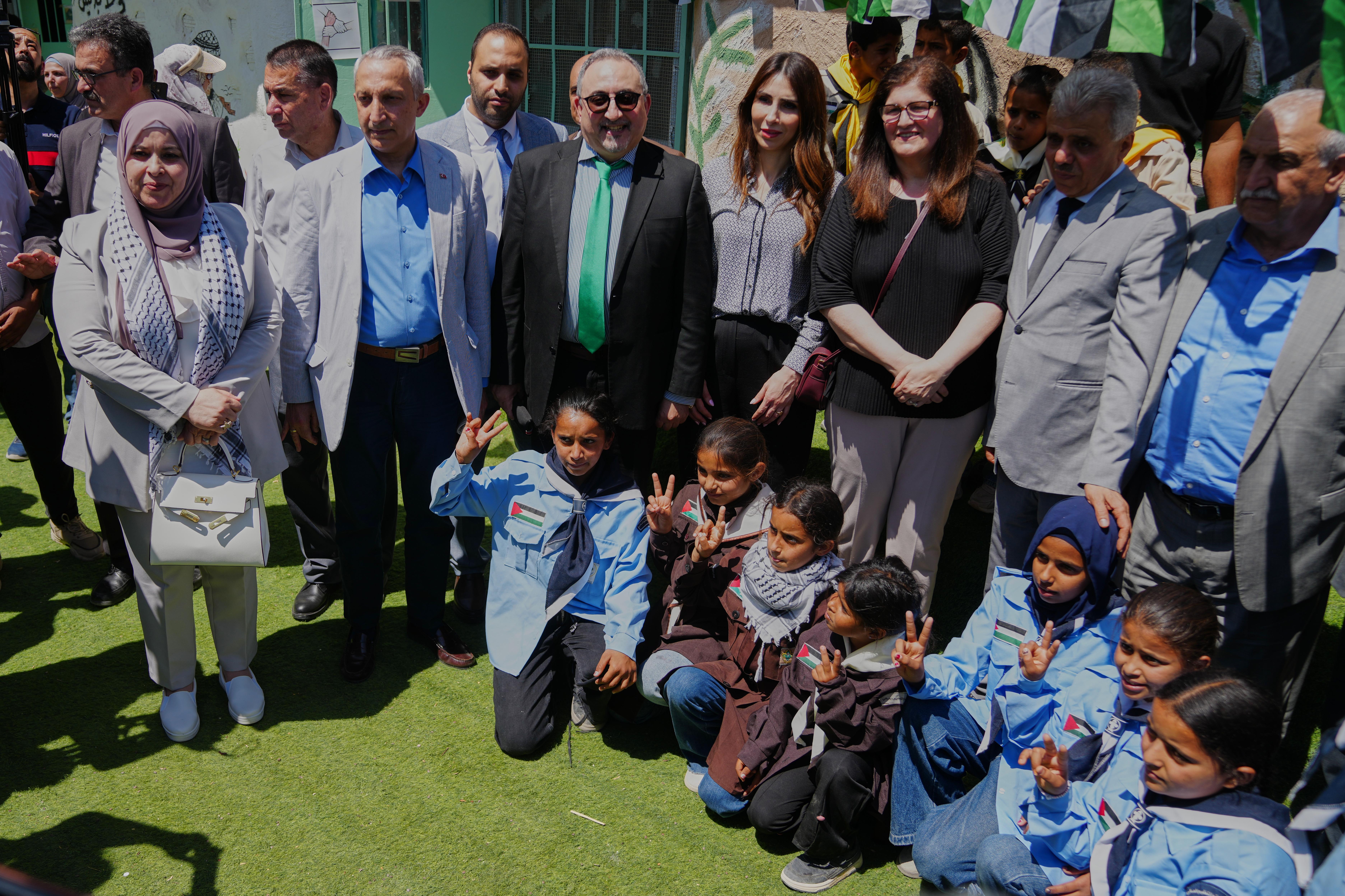 Palestinian officials and foreign diplomats take a photo with school children.