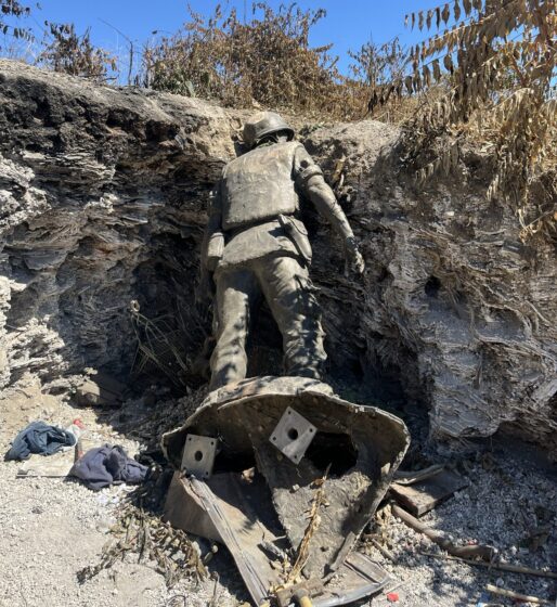 A vandalized statue found in a rocky embankment.