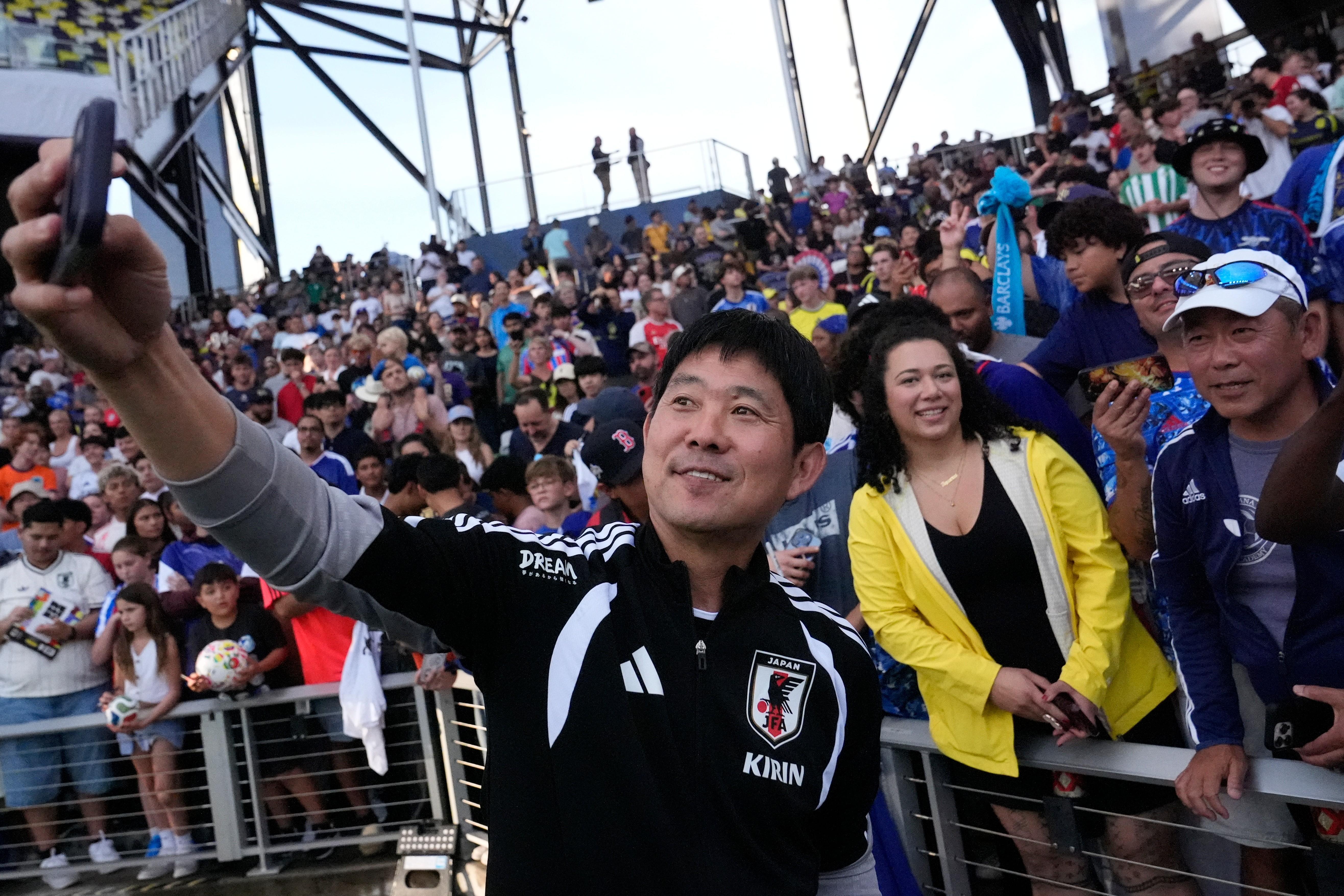 Japan head coach Hajime Moriyasu takes a picture with fans.