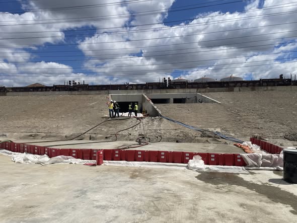 A containment boom is in place in the Los Angeles River and at multiple locations to maintain containment of crude oil in the waterway. Workers work to recovery oil from the waterway at multiple locations utilizing skimmers and vacuum trucks. Crews are also working to remove impacted vegetation, with efforts in place to maximize potential regrowth as seen here on May 29, 2026. (photo by Office of Spill Prevention and Response.)
