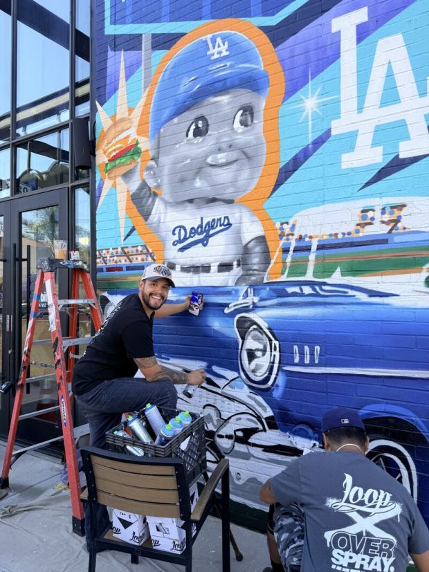 Muralist Alex Gonzalez in front of his mural at the the Habit's Dodger-themed restaurant dubbed Dodgers x Habit Home Base. (Photo courtesy Habit)