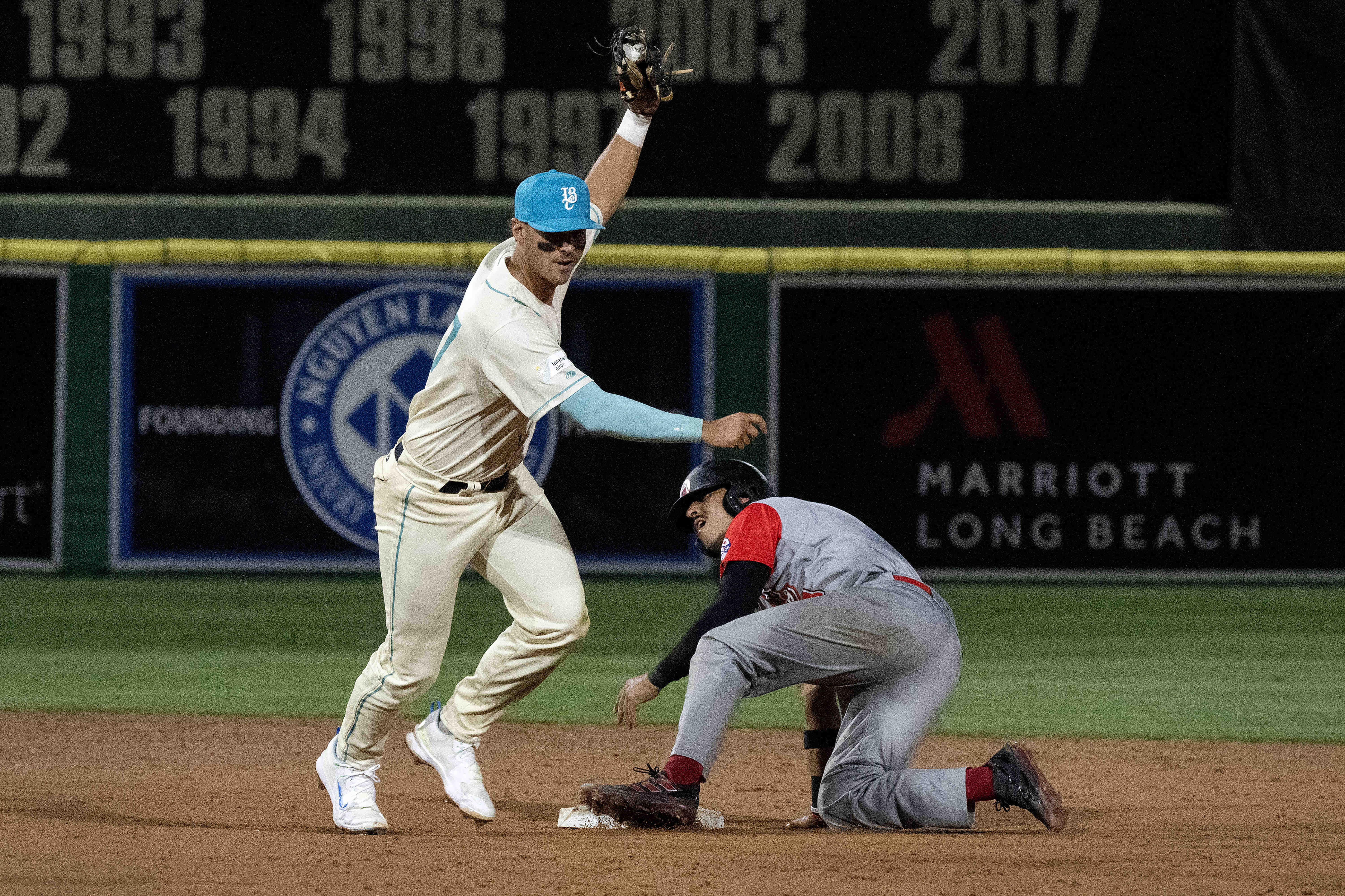 From left, Long Beach Coastâs Jacob Jablonski tags out the...