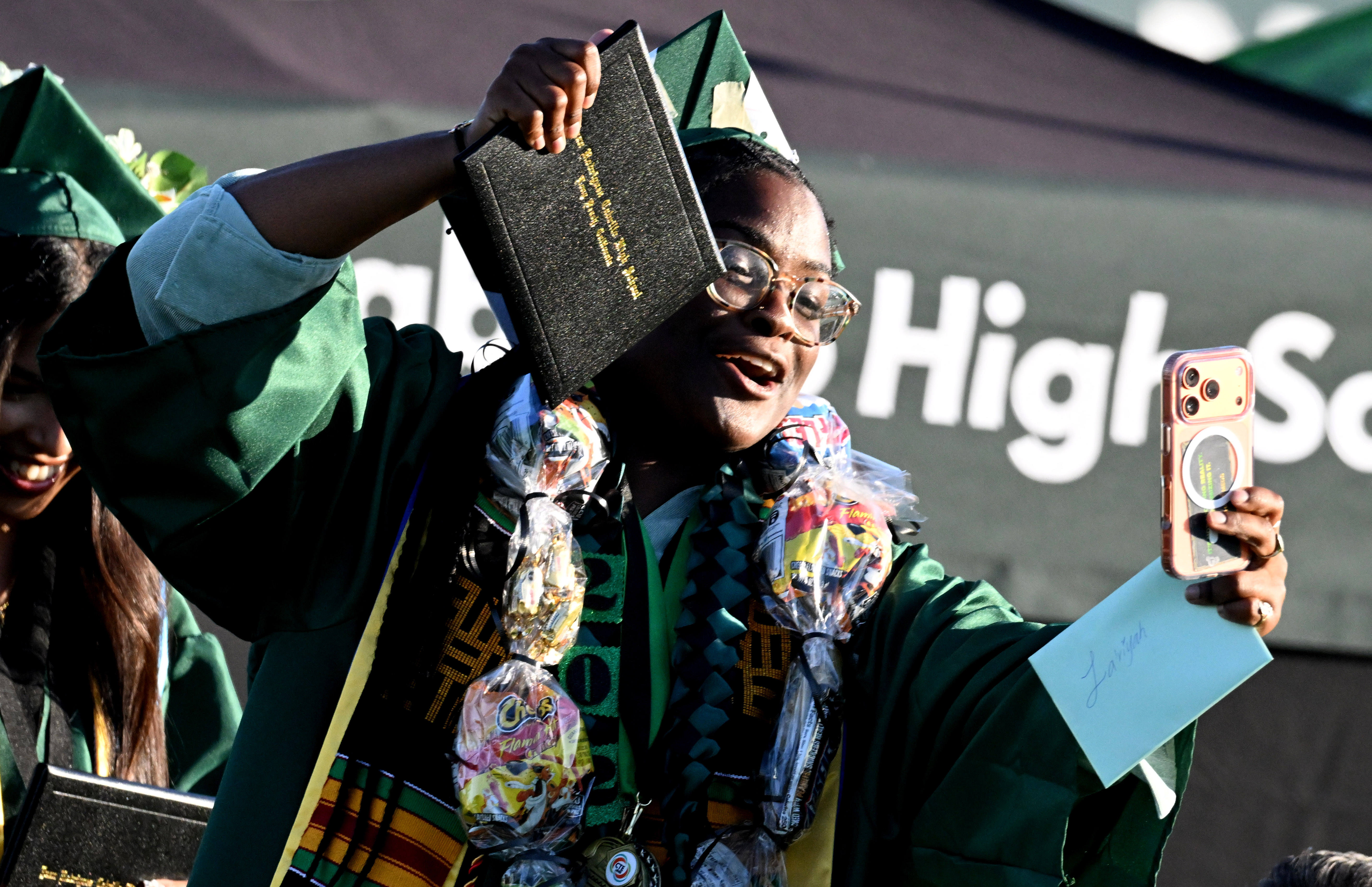 A senior takes a selfie after receiving his diploma during...