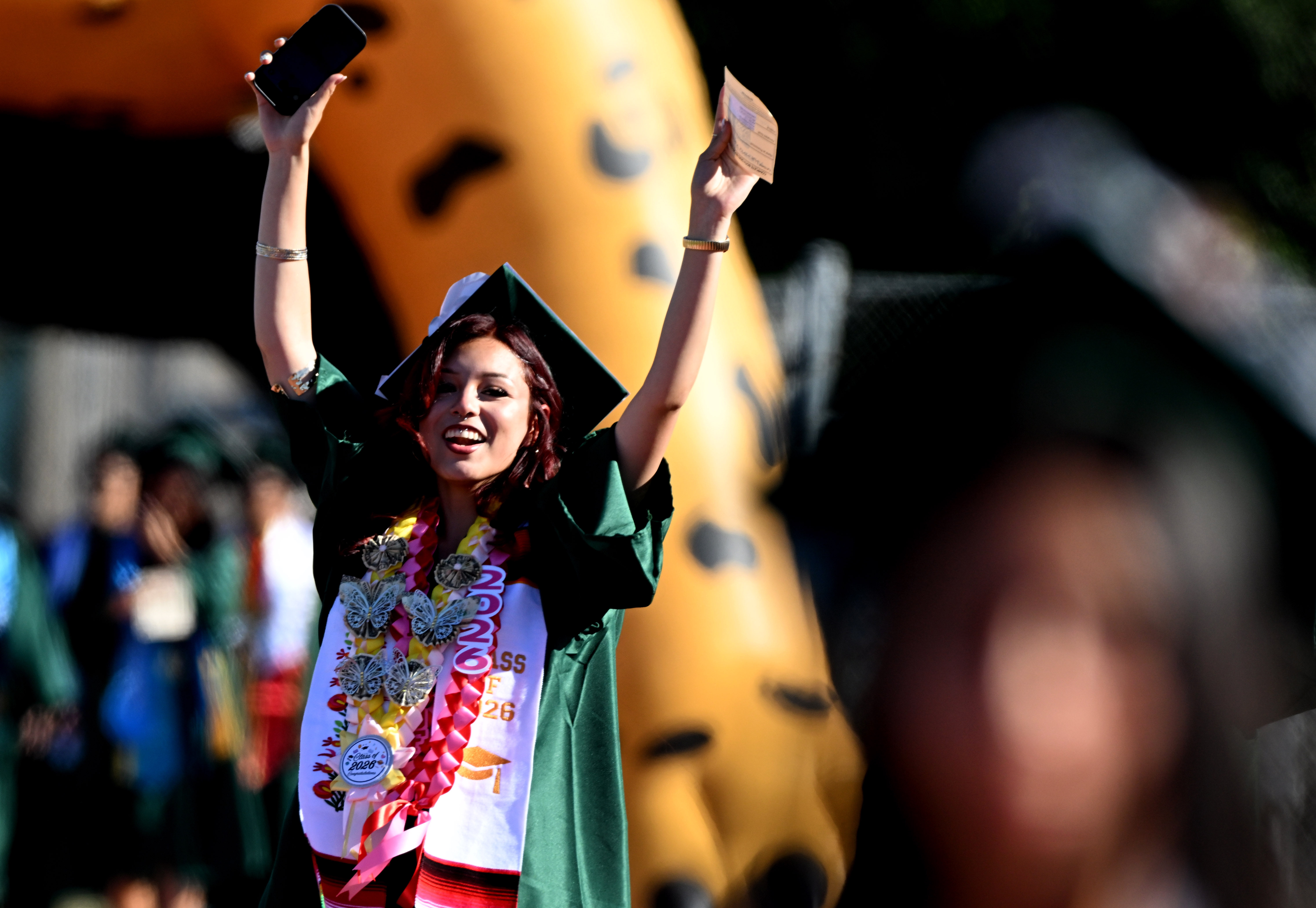 A senior waves to her family as she enters the...