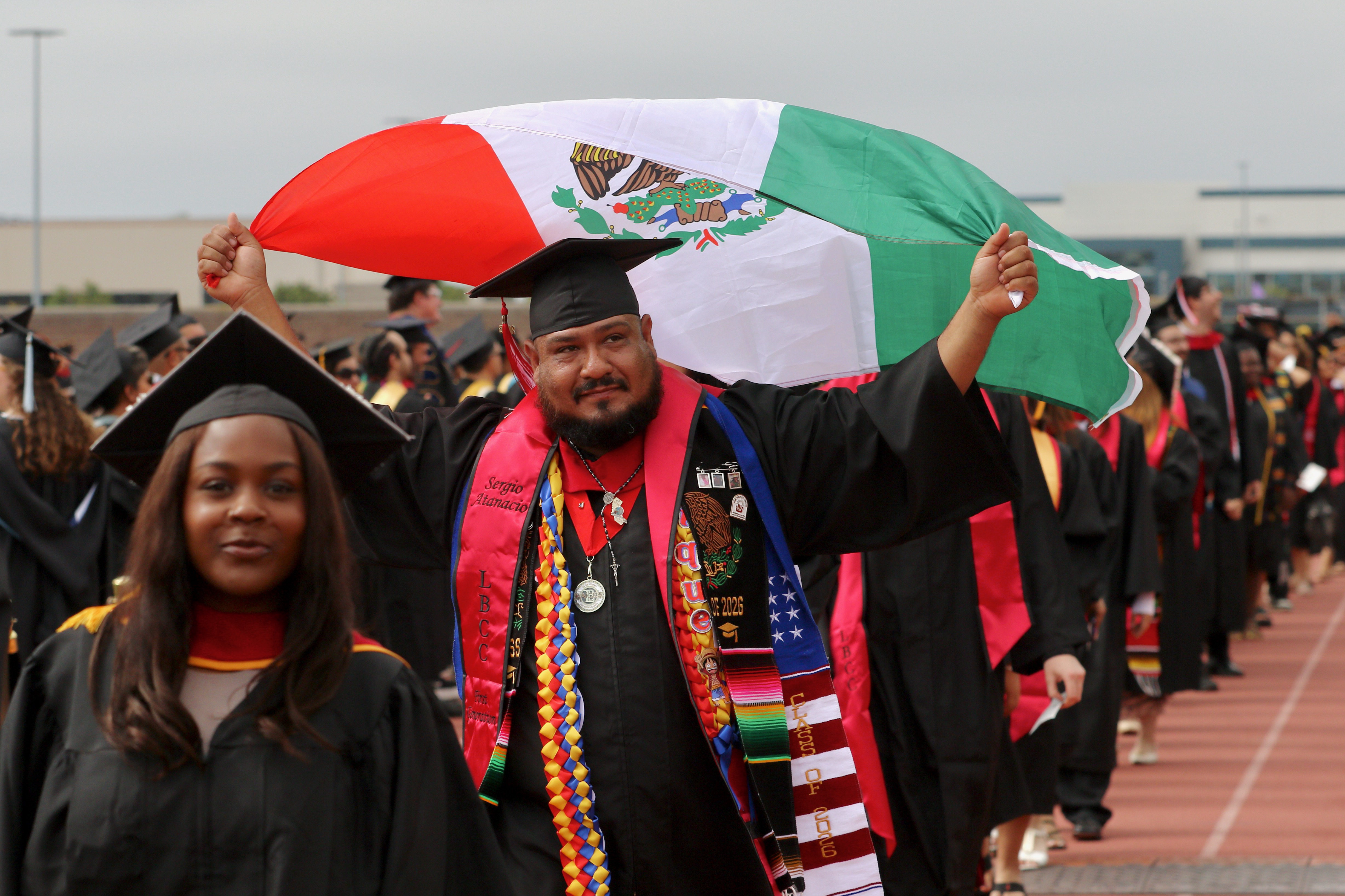 A graduate enters carrying the flag of Mexico at Long...
