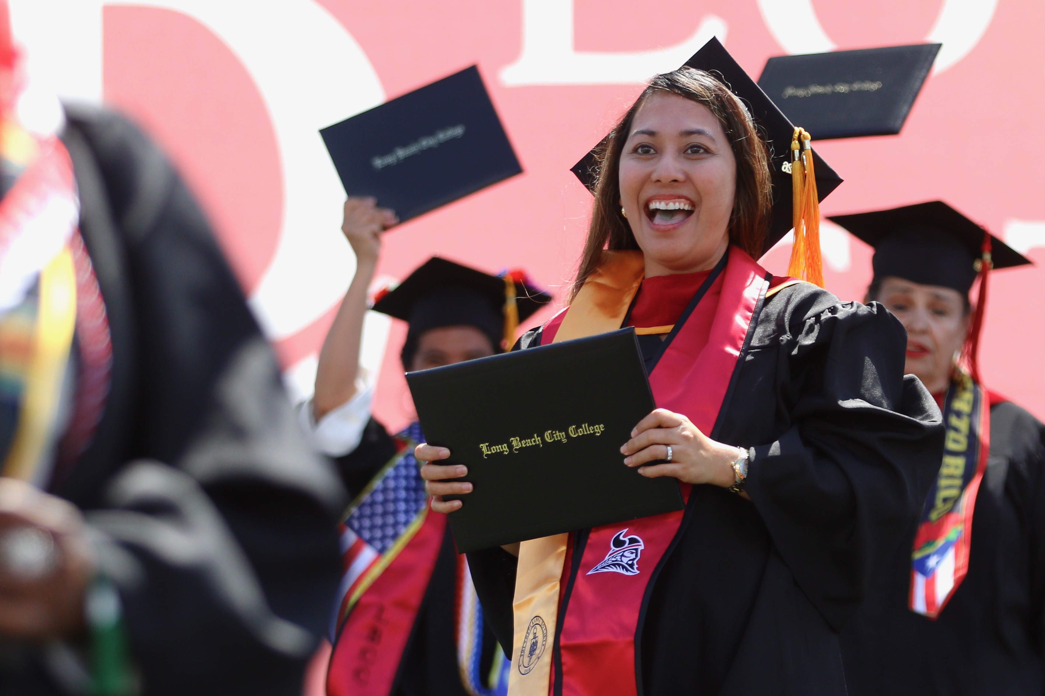Graduates walks off the stage with diplomas in hand at...