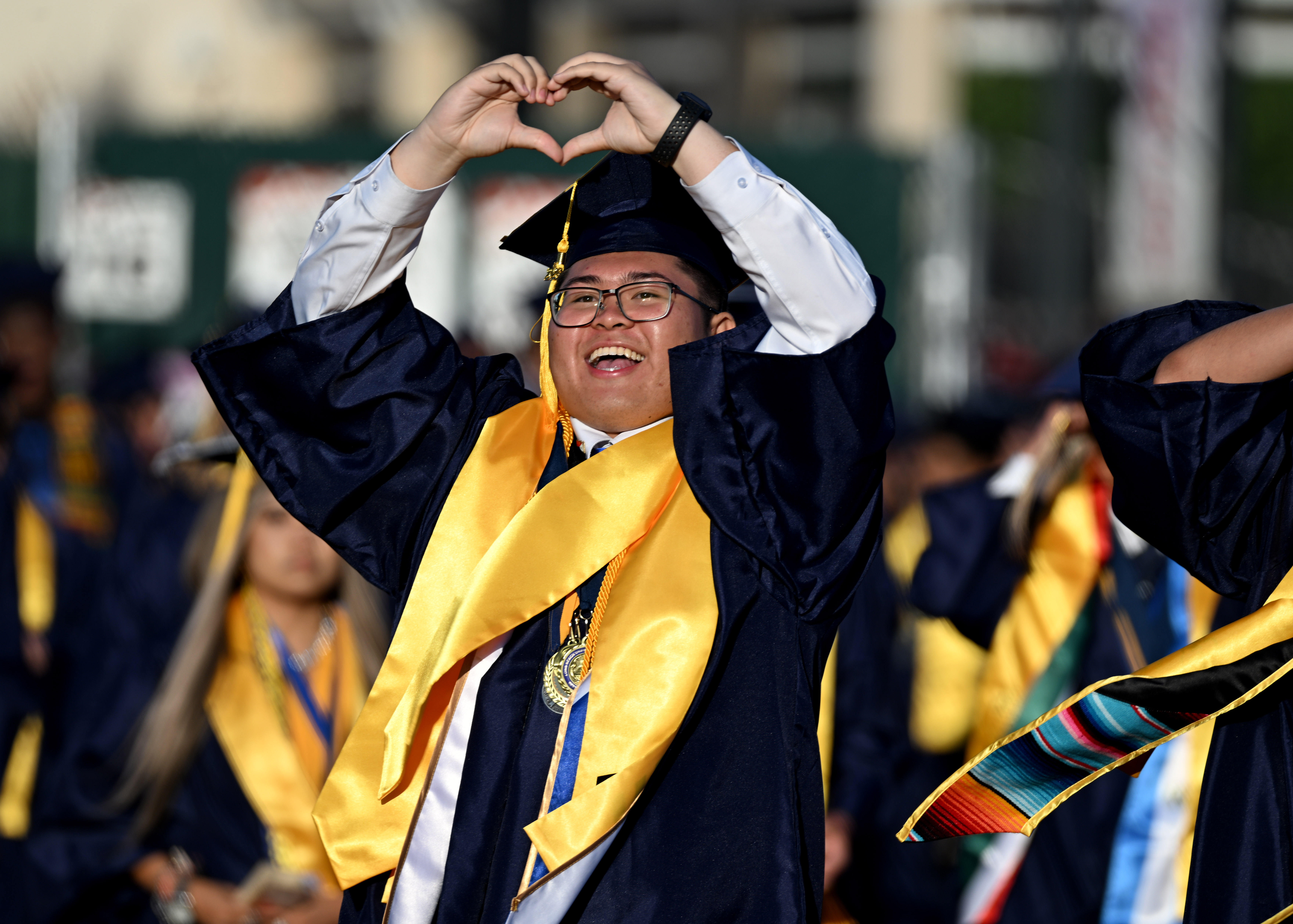 Senior Nathan Dabu makes a heart as he enters the...