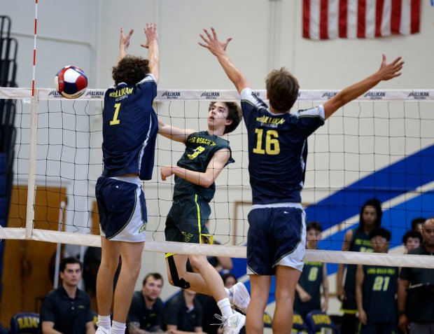 Long Beach Poly's Nicholas Frank (3) hits the ball past Millikan's Jacob Karkanen (1) and Evan Crucil Chambers (16) in Long Beach, CA, on Tuesday, March 24, 2026. (Photo by Tracey Roman, Contributing Photographer)
