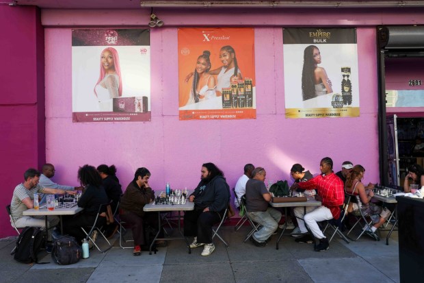 Festivalgoers play chess outside a beauty shop during the Oakland First Fridays event along Telegraph Avenue in Oakland, Calif., Friday, April 3, 2026. (Ray Chavez/Bay Area News Group)